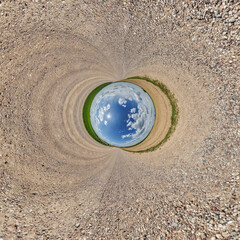 creative tiny planet photo of a rural landscape with dirt road, green fields, and cloudy sky...