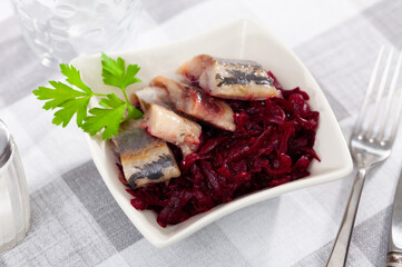Sliced herring with beetroot served table. Chopped fish with grated beet on table.