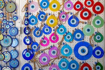 A vibrant assortment of evil eye amulets in various colors and shapes displayed on a wall,...