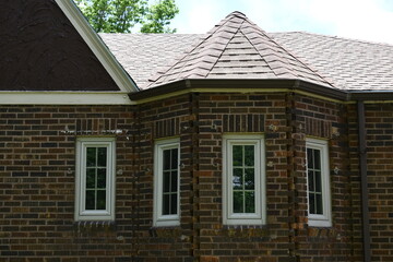 Classic style architecture. Reading nook built into home, tall windows, brick construction, peaked roof.