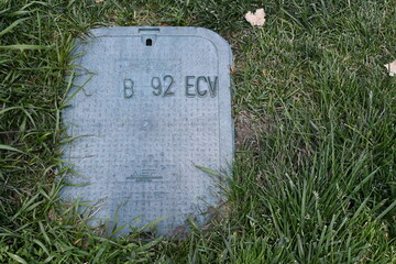 Irrigation control valve under plastic cover in ground.