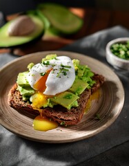 Poached egg atop crispy rye toast with bright avocado chunks, all bathed in warm morning sunlight that highlights the creamy textures and fresh, vibrant colors of the wholesome breakfast.