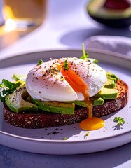 Poached egg atop crispy rye toast with bright avocado chunks, all bathed in warm morning sunlight that highlights the creamy textures and fresh, vibrant colors of the wholesome breakfast.