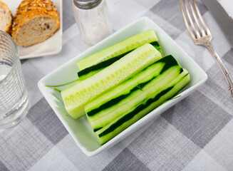 Peeled sticks long pieces of juicy cucumber pulp are laid out on plate. Vegetable snack, vegan side...