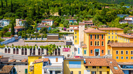 Aerial view of Salo, Italy with terracotta rooftops, lakeside promenade, and boats docked on the shore of Lake Garda on a sunny summer day