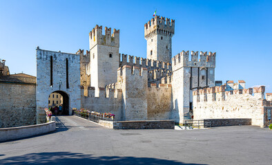 Aerial view of historic Scaliger Castle in Sirmione, Italy, surrounded by mountains