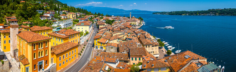 Aerial view of Salo, Italy with terracotta rooftops, lakeside promenade, and boats docked on the...