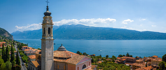 Aerial view of a pink historic church with bell tower in Gargnano, Lake Garda, Italy, surrounded by...
