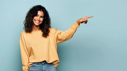 Smiling woman pointing finger to side against light blue empty background, adult girl model, young female person showing direction - Powered by Adobe
