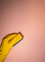 A person is holding a sponge and a yellow rubber glove. Concept of cleanliness and organization