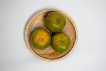 Natural citrus fruits displayed on a rustic round wood tray.