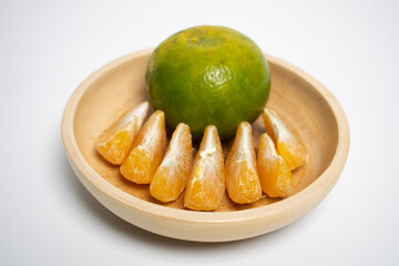 Citrus fruit neatly arranged in a wooden bowl on a white background.