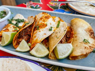 Delicious barbacoa tacos served with lime wedges and cilantro on a plate