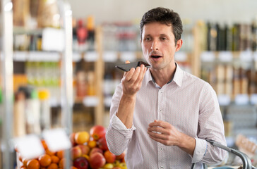 In store, male customer records audio message, communicates with friend and reports news in...