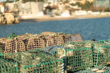Stacked crab traps sit on the dock as the sun sets over the water, preparing for a night of crabbing. The vibrant colors of the sky reflect on the surface, creating a serene atmosphere.