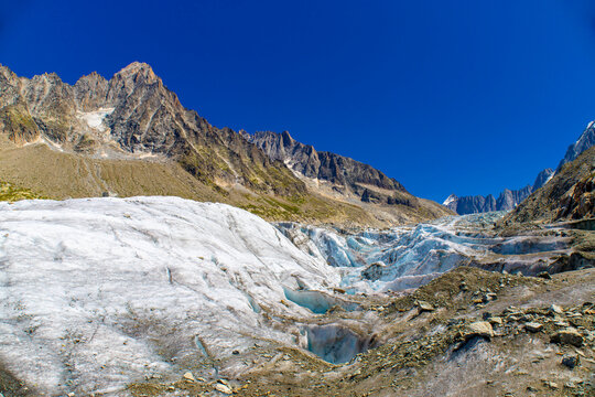 Glacier Argentiere in Chamonix valley, french Alps. Blue ice in a glacier serac and crevasse in the alpine scenic landscape in summer. Aiguille du Chardonnet mountain summit peak above the glacier