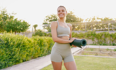 A smiling fitness enthusiast practices yoga in a sunlit garden, surrounded by greenery