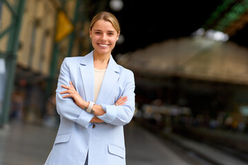 A confident businesswoman at a busy train station, showcasing her stylish demeanor and ambition