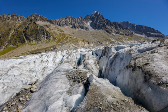 Glacier Argentiere in Chamonix valley, french Alps. Blue ice in a glacier serac and crevasse in the alpine scenic landscape in summer. Aiguille du Chardonnet mountain summit peak above the glacier