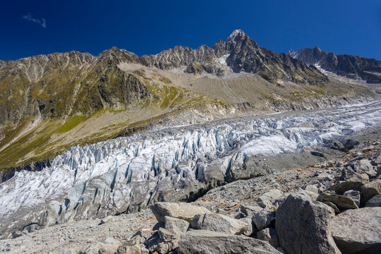 Glacier Argentiere in Chamonix valley, french Alps. Blue ice in a glacier serac and crevasse in the alpine scenic landscape in summer. Aiguille du Chardonnet mountain summit peak above the glacier