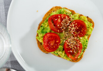 Sandwich with guacamole butter, tomatoes and seeds on whole grain bread, healthy eating concept