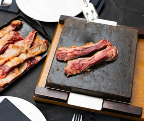Meat grilling on hot stone on table, preparation of original lunch or dinner