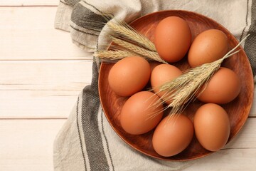 Fresh eggs and spikes on light wooden table, top view. Space for text