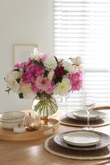 Beautiful table setting with bouquet of peonies in dining room, closeup