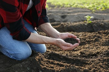 Man holding pile of soil in field, closeup