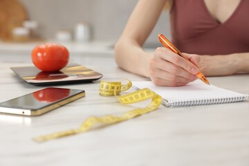 Woman developing diet plan at white marble table indoors, closeup
