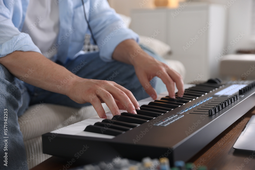 Poster man working with midi keyboard at table indoors, closeup