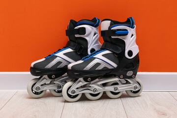 Pair of roller skates on floor near orange wall