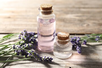 Natural essential oil and lavender flowers on wooden table, closeup