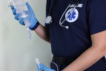 Woman paramedic holding a fluid intravenous bag with the infusion set to be infused in an urgency.