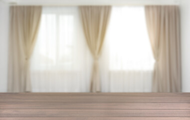 Empty wooden table against windows with curtains in room