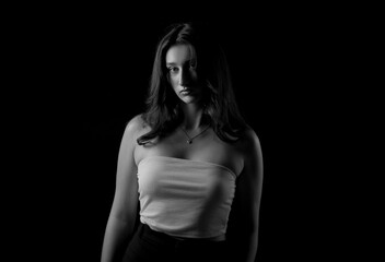 Studio portrait of a young woman wearing a tube top and posing against a black background