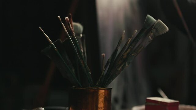 Artist Picks Up a Paint Brush in a Moody Studio Medium Shot