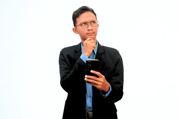 An Asian business man holding a cell phone with a thoughtful expression.