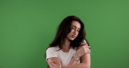 Studio shot of a sad young woman hugging herself with closed eyes, feeling insecure and lonely...