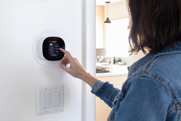 Smart thermostat. Woman setting up smart thermostat schedule.