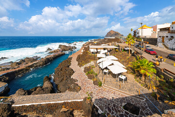 Waterfront cafes along the rocky volcanic coastline at the seaside town of Garachico, Spain, on the...