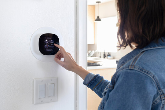 Smart thermostat. Woman setting up smart thermostat schedule.