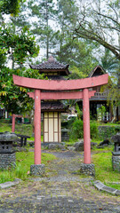 A traditional red torii gate stands at the entrance to a Japanese-style garden