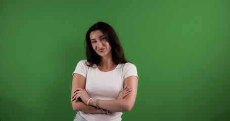 Young woman with crossed arms smiles slightly on chroma key background, ideal for advertising and...