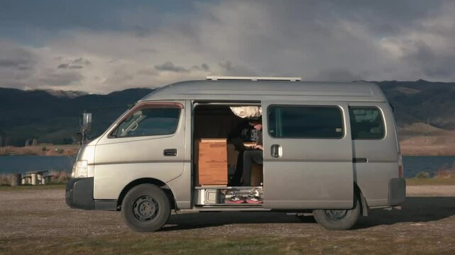Side view of a nomadic man working on a laptop in his van