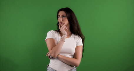 Pensive young woman with hand on chin looking away against chroma key background