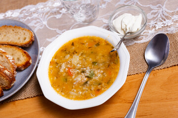 Soup with pickled cucumbers and pearl barley - rassolnik on wooden background.