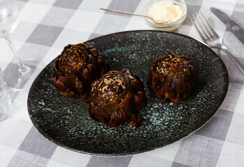Popular dish of Mediterranean cuisine is appetizing artichokes on a plate, served with sauce....