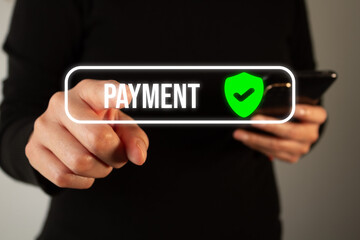 A businesswoman holds her smartphone while with her other hand points to a virtual button of a shield with a check mark and the word "Payment"