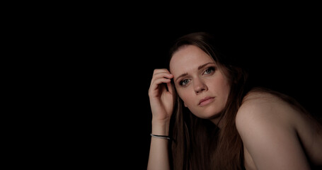 Obraz premium Portrait of a young Caucasian woman posing with her hand on her head on black background